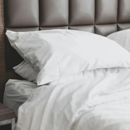 Close-up of an ivory sateen pillowcase against a padded headboard