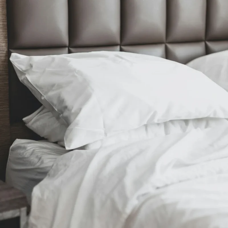 Close-up of an ivory sateen pillowcase against a padded headboard