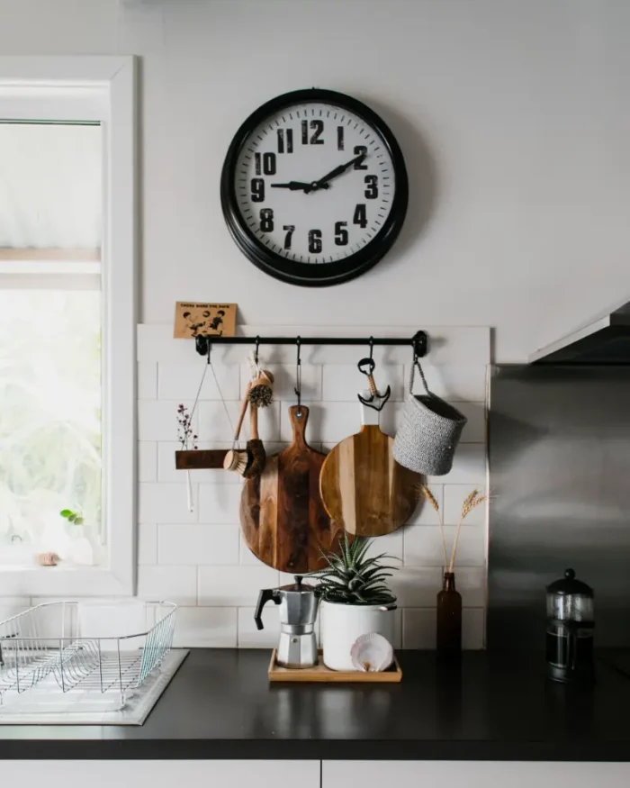 Halo minimal wall clock with a black frame above hanging utensils in a bright modern kitchen
