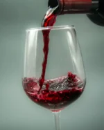 Red wine being poured into a Lumière crystal wine glass, showing the fine rim and generous bowl