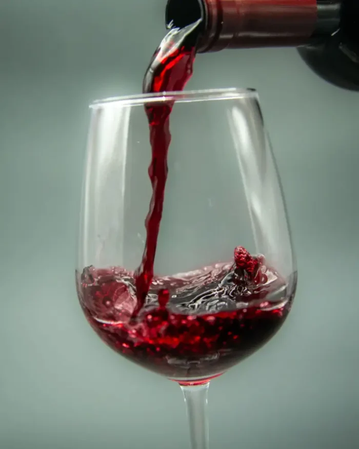 Red wine being poured into a Lumière crystal wine glass, showing the fine rim and generous bowl