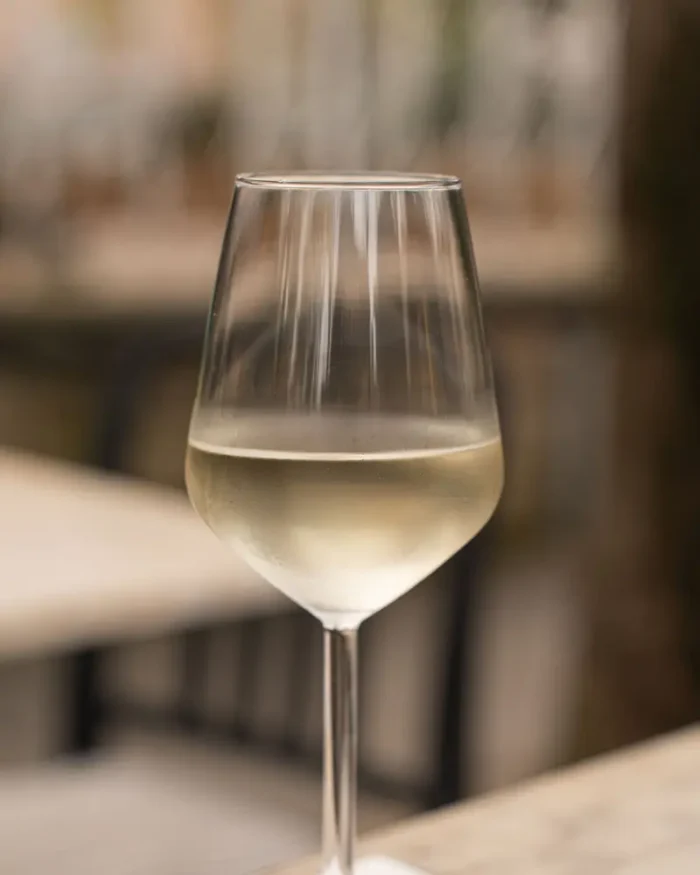 Lumière crystal wine glass filled with chilled white wine on a minimalist table in soft light