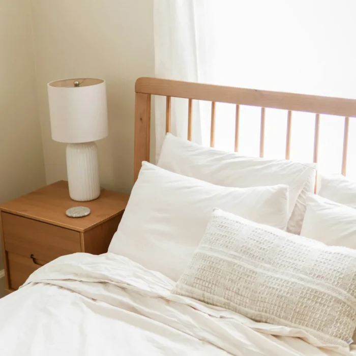 Bright bedroom styled with ivory sateen bedding and a wooden headboard