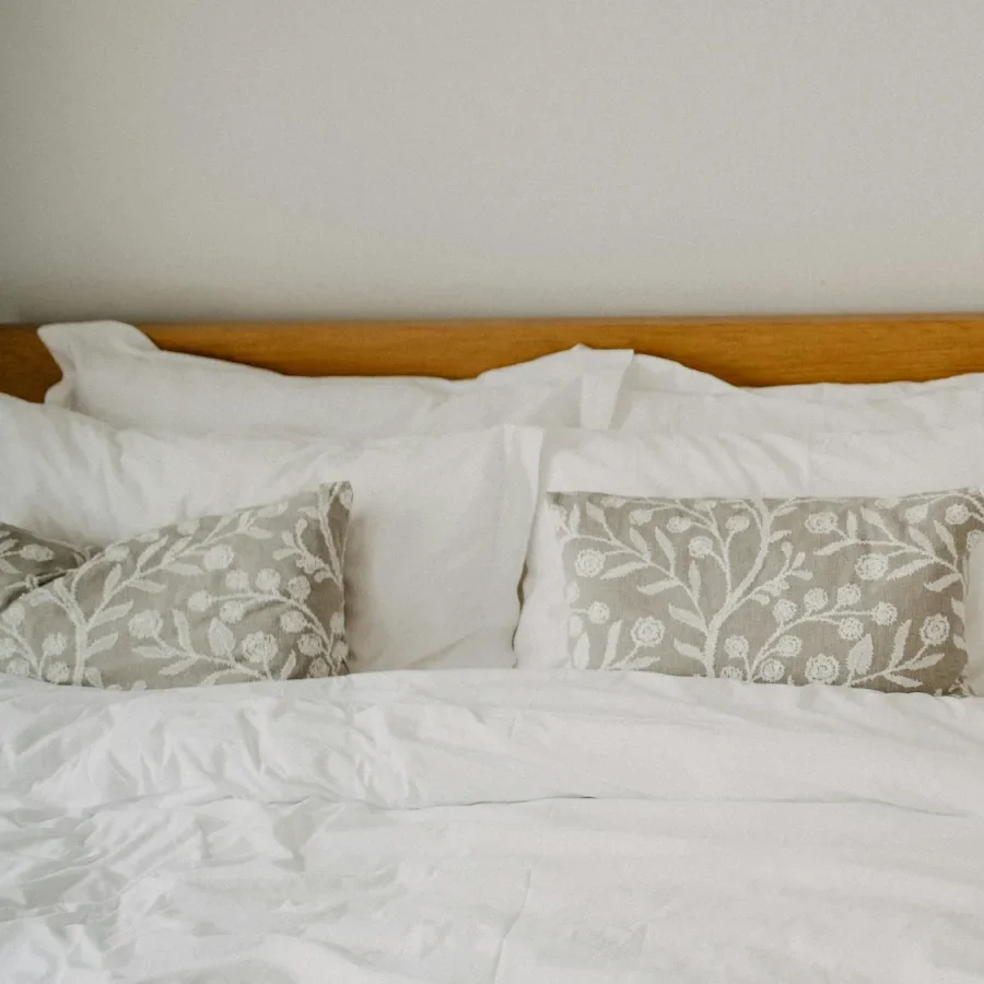 Calm, neatly made bedroom with ivory sateen bedding and a bedside table