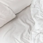 Soft drape and fold of white sateen bed linen