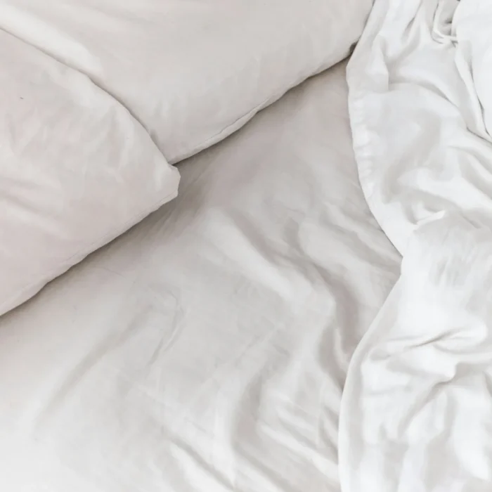 Soft drape and fold of white sateen bed linen
